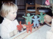 Kleines Mädchen staunend mit Plastikspielfiguren der 80er